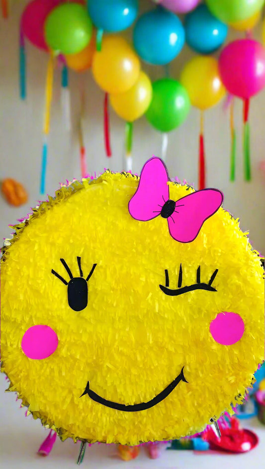 Smiley face piñata with a pink bow 
